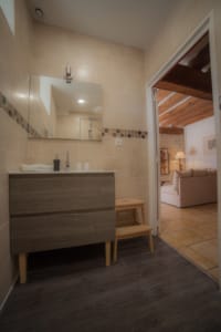 Salle de bain lumineuse avec miroir et grande vasque dans la suite Écurie